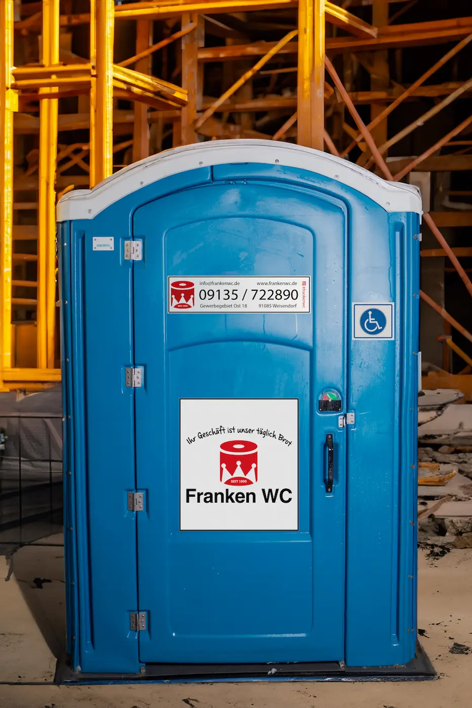 Franken-WC-dixi-klo-mieten-blau-aussenansicht-vor-gelben-baugeruest-toilette-barrierefrei